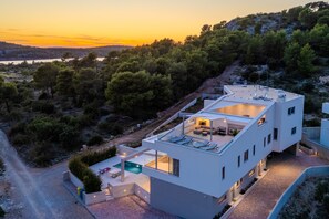 Ein modernes, zweistöckiges Gebäude mit Dachterrasse und Swimmingpool.