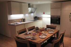 A modern kitchen with a dining table set for breakfast, including plates, cups, and a coffee maker. - Holiday apartment with 2 bedrooms (Rietzlern)