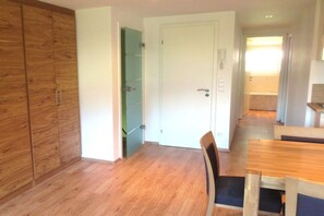 A room with a wooden wardrobe, a white door, and a dining table with chairs. - Holiday apartment with 2 bedrooms (Rietzlern)