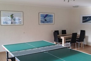 A room with a ping pong table, a dining table with chairs, and three framed pictures on the wall. - Holiday apartment with 2 bedrooms (Rietzlern)
