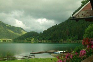 A lake with a wooden dock and boats, surrounded by forested hills. - Fisherman's dream by the lake (Nesselwängle)