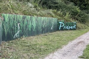 A sign with the word 'Priepert' on a green background with grass and a bird. - LEE Anchorage Priepert (Priepert)