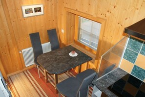 A compact kitchen with a dining area, wooden walls, a radiator, and a window with blinds. - Edelweiss Apartment, Family Wechselberger (Schwendau)