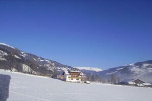 A snow-covered landscape with a building featuring a balcony and a mountain backdrop. - Edelweiss Apartment, Family Wechselberger (Schwendau)