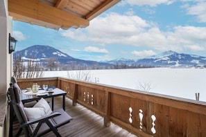 A wooden deck with a table and chairs, overlooking a snowy landscape with mountains. - Holiday apartment with 1 bedroom (Kirchdorf)