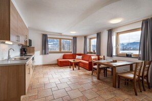 A modern kitchen with a dining area, a sofa, and a table with chairs. - Holiday apartment with 1 bedroom (Kirchdorf)