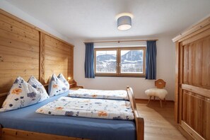 A room with a bed, a chair, a window with curtains, and a view of mountains. - Holiday apartment with 1 bedroom (Kirchdorf)