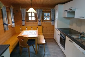 A compact kitchen with a wooden bench, a table, and a window with curtains.