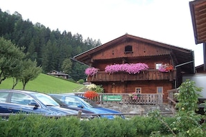 Ein Holzgebäude mit Balkonen, die mit Blumen geschmückt sind, einem Schild, das ein Restaurant anzeigt, und Autos, die vor dem Gebäude geparkt sind.