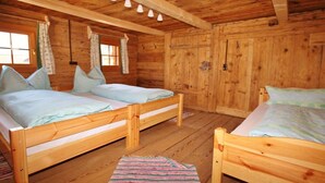 A cabin with two wooden beds, a window with curtains, and a wooden ceiling with hanging lights. - Holiday cabin Donnerhäusl (Hippach)