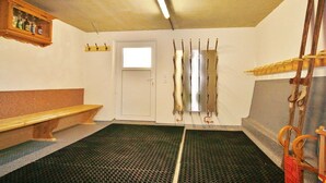 Een kamer met een bank, kapstok, deur en raam.