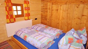 A wooden cabin room with a bed, curtains, and a window. - Holiday cabin Donnerhäusl (Hippach)