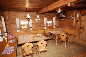 Un interior de madera con una zona de asientos con banco, mesas y sillas.