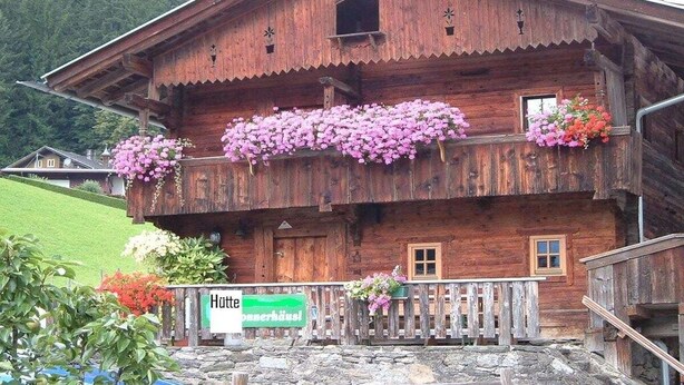 A wooden building with a balcony adorned with flowers, a sign indicating it is a hotel, and a stone staircase leading to the entrance. - Holiday cabin Donnerhäusl (Hippach)