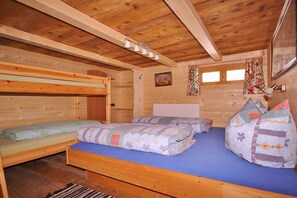 Interior de una cabaña de madera con literas, un colchón azul y un radiador.