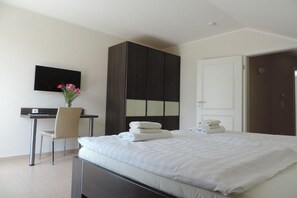 A hotel room with a bed, a desk, a chair, a television, and a wardrobe. - Holiday home with 2 bedrooms (Göhren-Lebbin)