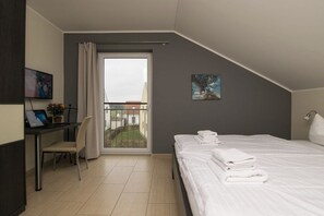 A hotel room with a bed, a desk, a chair, a balcony with a view, and artwork on the walls. - Holiday home with 2 bedrooms (Göhren-Lebbin)