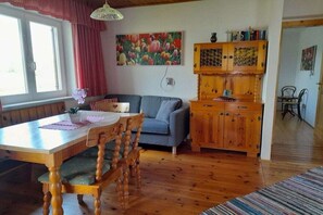 Ein Essbereich mit Holztisch und Stühlen, einem Sofa und einem Schrank mit einem floralen Gemälde darüber.