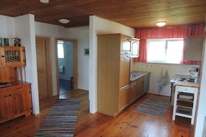Eine Küche mit Holzausstattung, einem Kühlschrank und einem Fenster mit rotem Vorhang.
