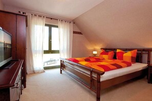 A bedroom with a bed, a television, and a window with curtains. - Holiday apartment with 1 bedroom (Usedom)