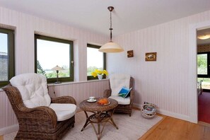 A room with two wicker chairs, a small round table, and a hanging light fixture. - Holiday apartment with 1 bedroom (Usedom)