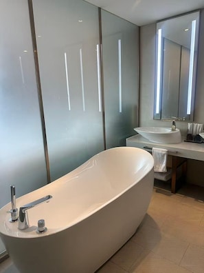 Un baño moderno con una bañera independiente, un lavabo y un espejo.