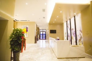 A hotel lobby with a reception desk, a potted plant, and a wall-mounted television. - Lavande Hotels Harbin Railway Station Zhanqian Square (Harbin)
