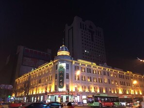 A multi-story building with a prominent dome and illuminated signage. - Lavande Hotels Harbin Railway Station Zhanqian Square (Harbin)