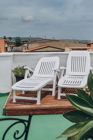 Zwei weiße Lounge-Stühle auf einer Holzdiele mit Blick auf die Skyline im Hintergrund.