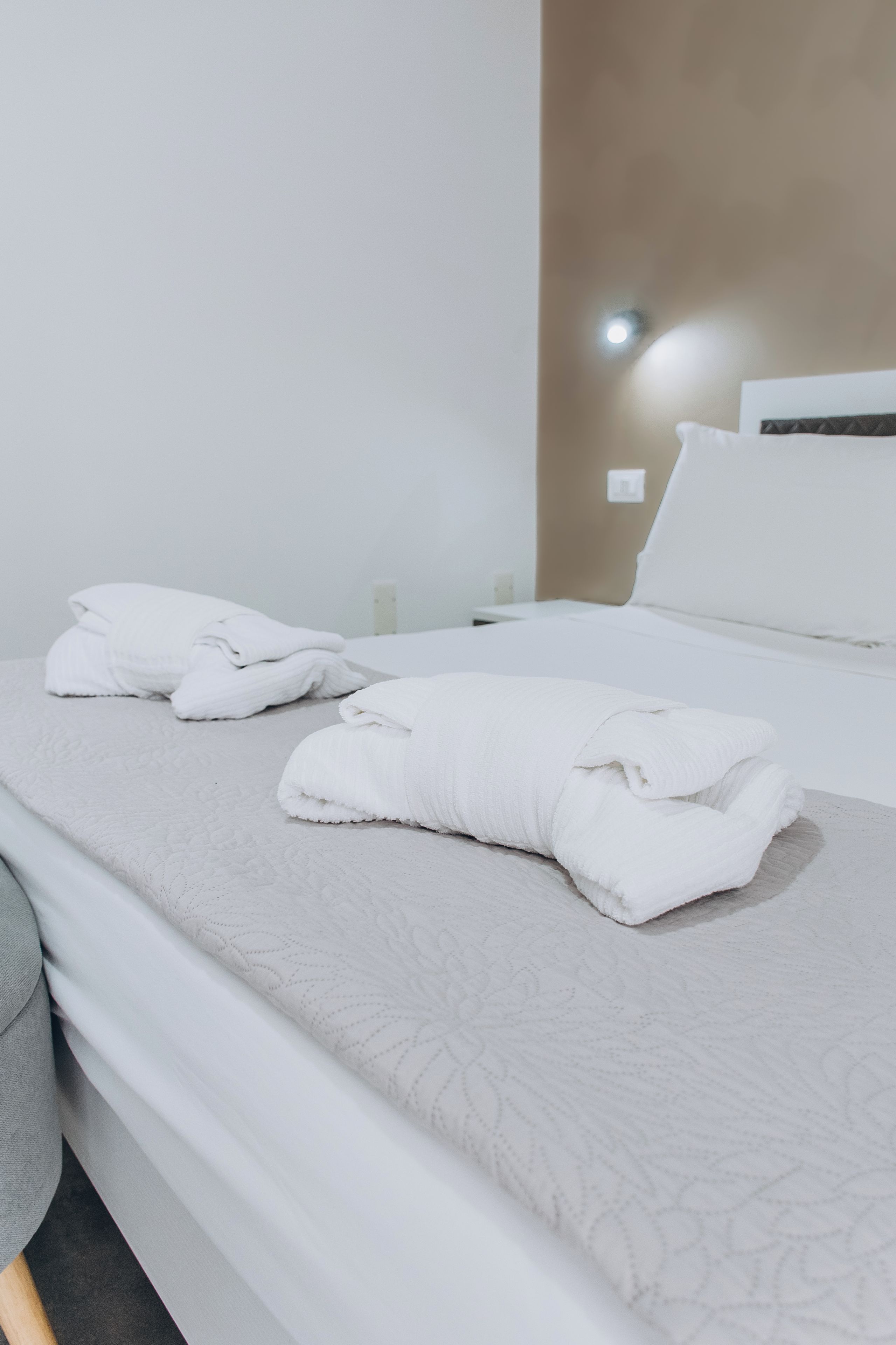 Un letto rifatto con lenzuola bianche e copripiumino decorato.