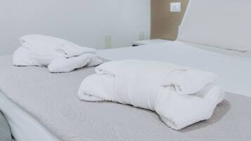 Un letto rifatto con lenzuola bianche e copripiumino decorato.