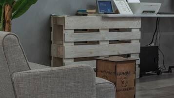Un soggiorno moderno con una poltrona grigia, una cassa di legno e una pianta in vaso.