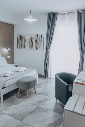Una camera da letto moderna con un letto, una sedia, una scrivania e un quadro appeso al muro.