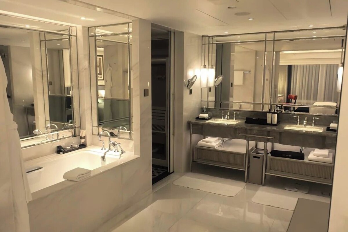 A modern bathroom with a large mirror, a bathtub, and a vanity with a sink.
