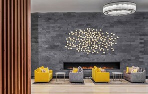 Una sala moderna con chimenea, un candelabro y tres sofás dispuestos al frente.