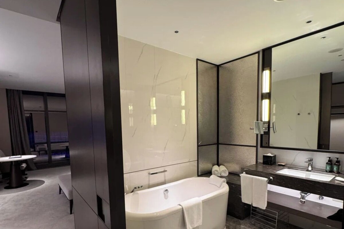 A modern bathroom with a freestanding bathtub, a large mirror, and a vanity with a sink.
