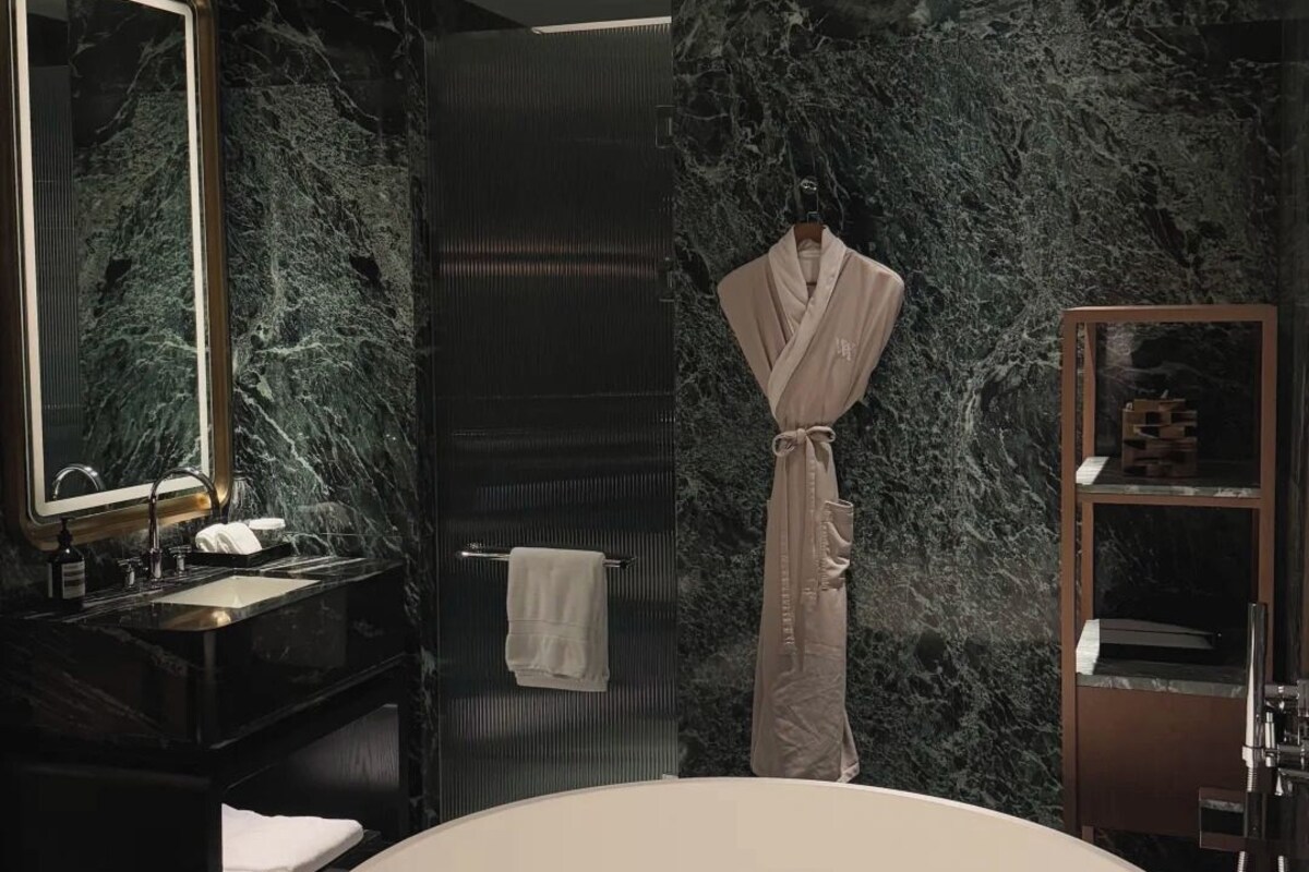 A modern bathroom with a large freestanding bathtub, a vanity with a mirror, and a robe hanging on a hook.