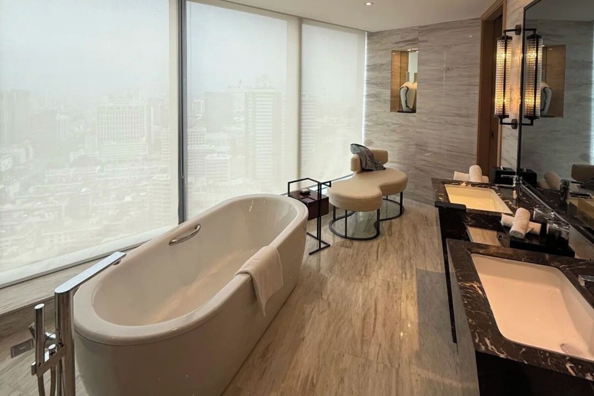 A modern bathroom with a freestanding bathtub, a vanity with two sinks, and a large mirror.