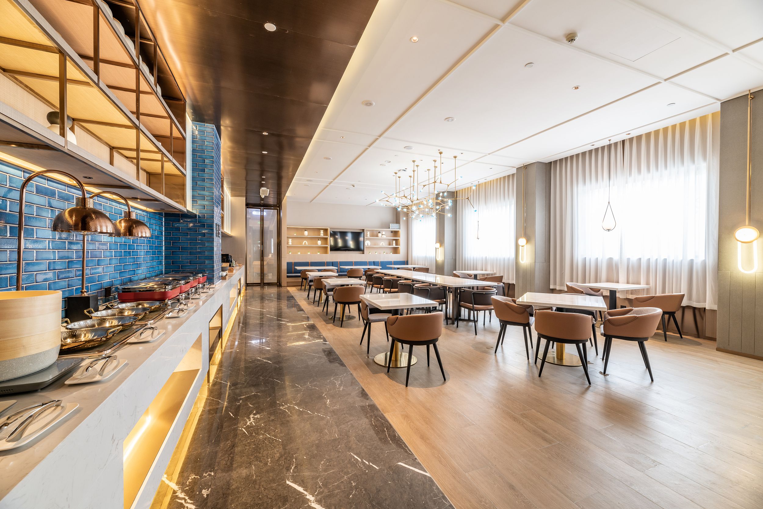 Un restaurant moderne doté d’un long comptoir, de plusieurs espaces de restauration et d’un éclairage combinant des sources naturelles et artificielles.