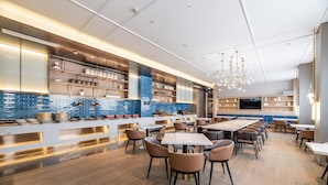 A modern restaurant with a long counter, multiple seating areas, and a variety of kitchenware displayed on shelves. - Yu'an Hotel Guangzhou Zhujiang New Town (Guangzhou)