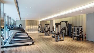 A modern gym with treadmills, weight machines, and a mirrored wall.