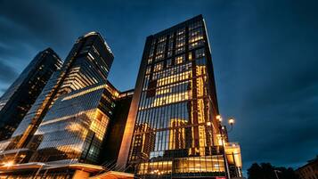 Un immeuble moderne de grande hauteur, doté de façades en verre réfléchissant et d’une entrée imposante surmontée d’un auvent.