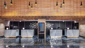 A modern reception area with marble counters, wooden slatted ceiling, and pendant lighting. - Yu'an Hotel Guangzhou Zhujiang New Town (Guangzhou)