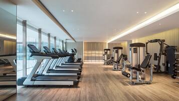 A modern gym with treadmills, weight machines, and a wooden floor.