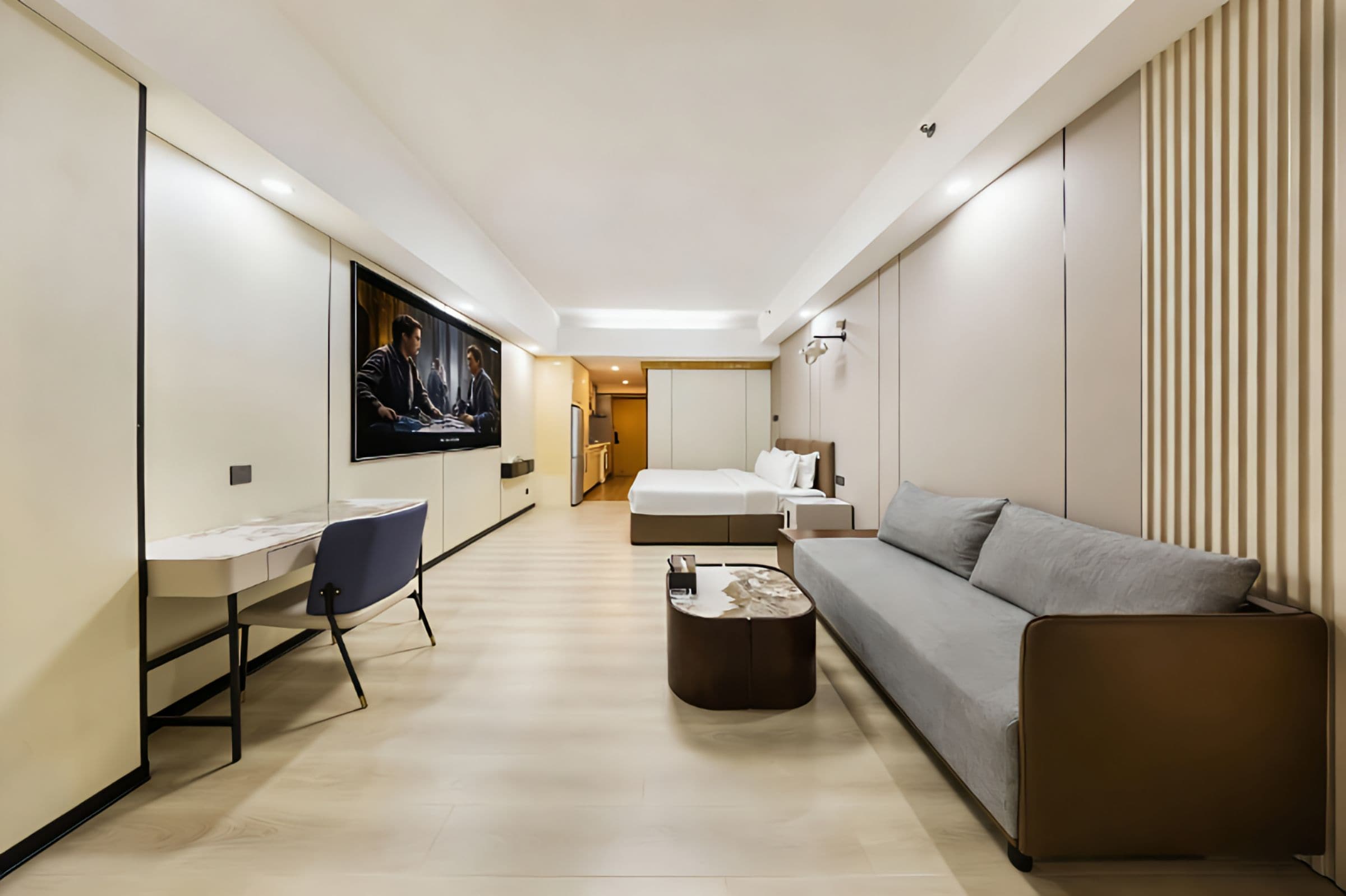 A modern hotel room with a bed, a sofa, a desk, and a television.