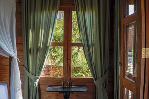 A wooden room with a window, curtains, and a table with two cups. - La Colline Nusa Penida (Penida Island)