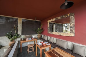 A room with a red wall, a large mirror, and a seating area with a table and chairs. - La Colline Nusa Penida (Penida Island)