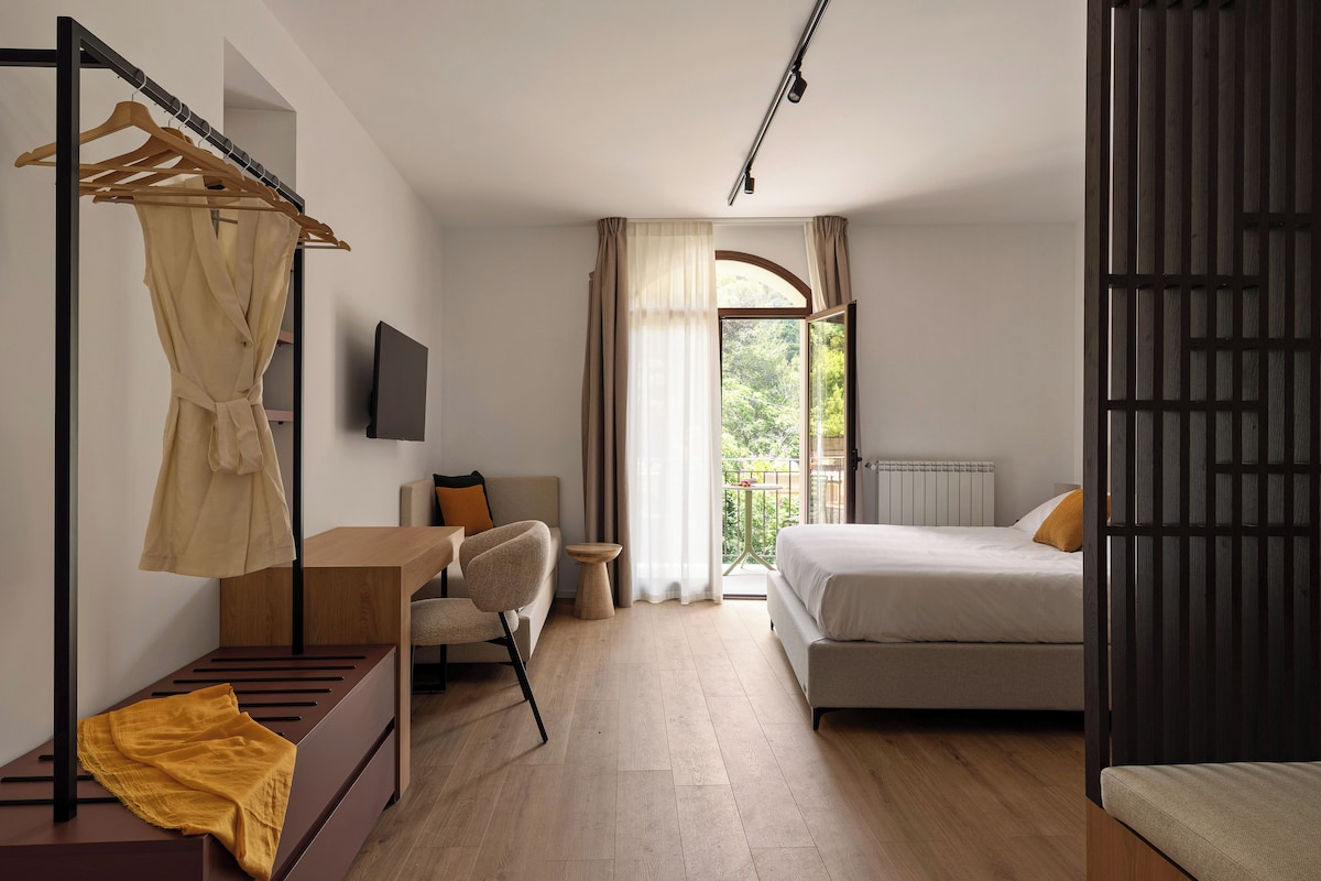 Un dormitorio moderno con cama, mesita de noche, una silla, armario y ventana con cortinas.