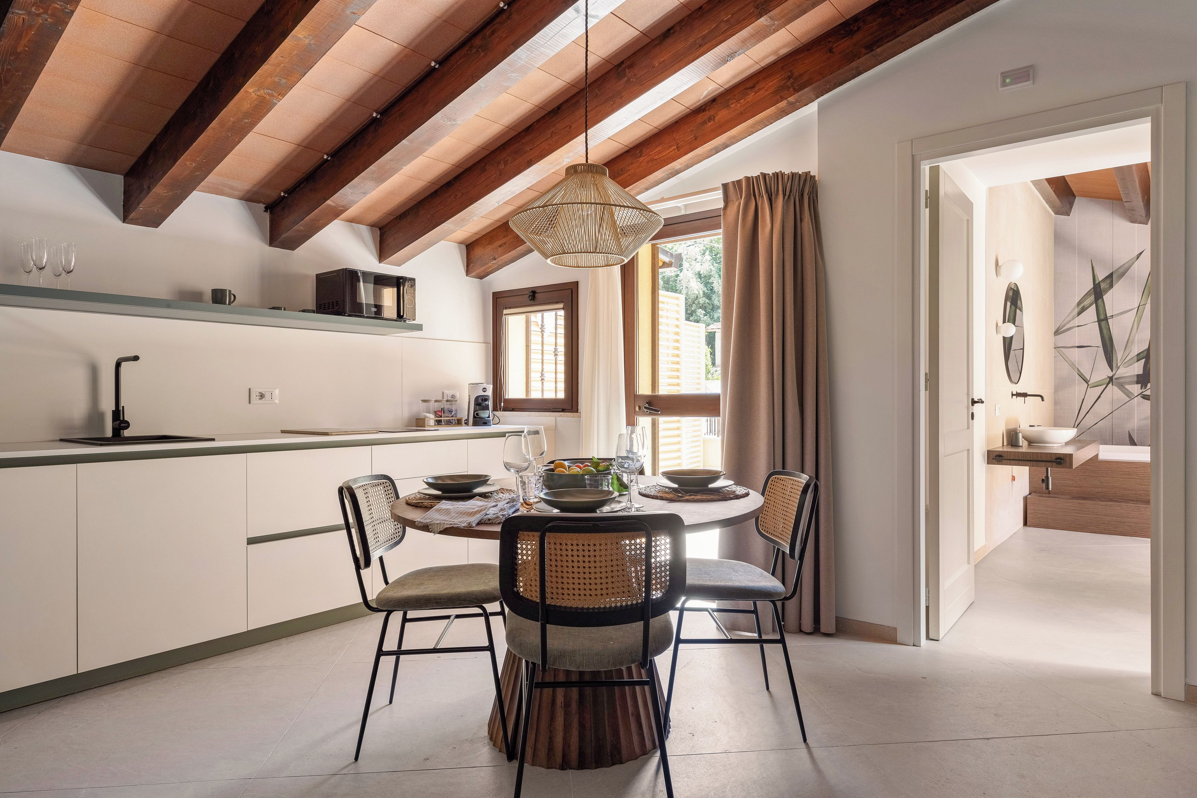 Una cocina moderna con comedor, vigas de madera y vistas al exterior.
