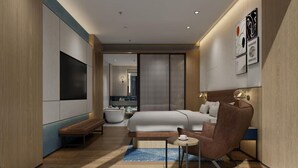 Ein modernes Hotelzimmer mit Bett, Sitzecke und Fernseher.